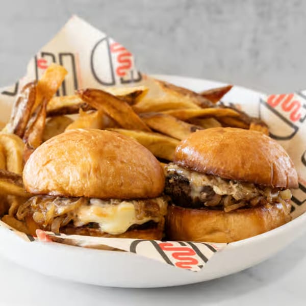 Two Wagyu Burger Shack sliders with melted cheese and caramelized onions, served with fries.